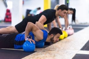 young-athletes-doing-pushups-with-kettlebells-A4XFRJ9
