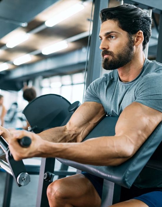 Strong ripped man training bicepses in gym